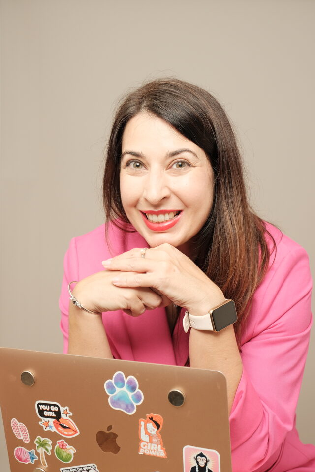 Kalina smiling behind her sticker-covered laptop